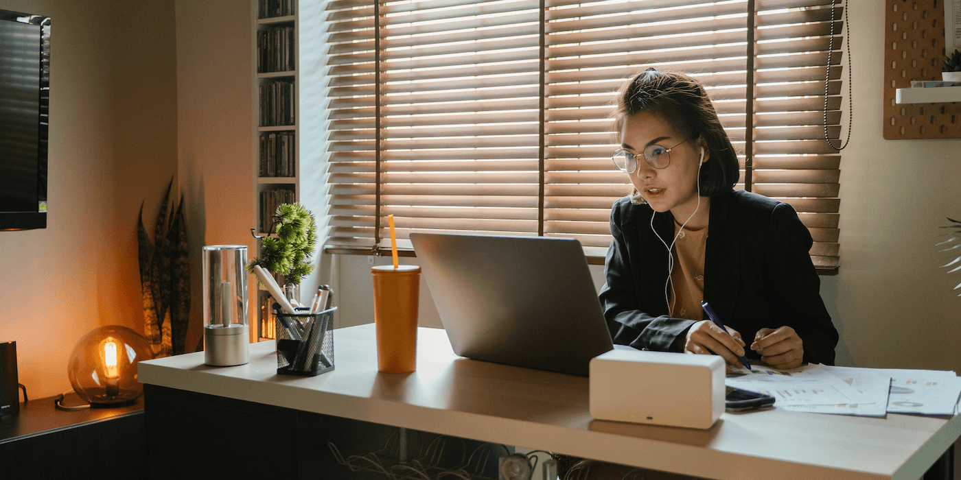 person sitting at desk at home looking at a laptop and papers nearby