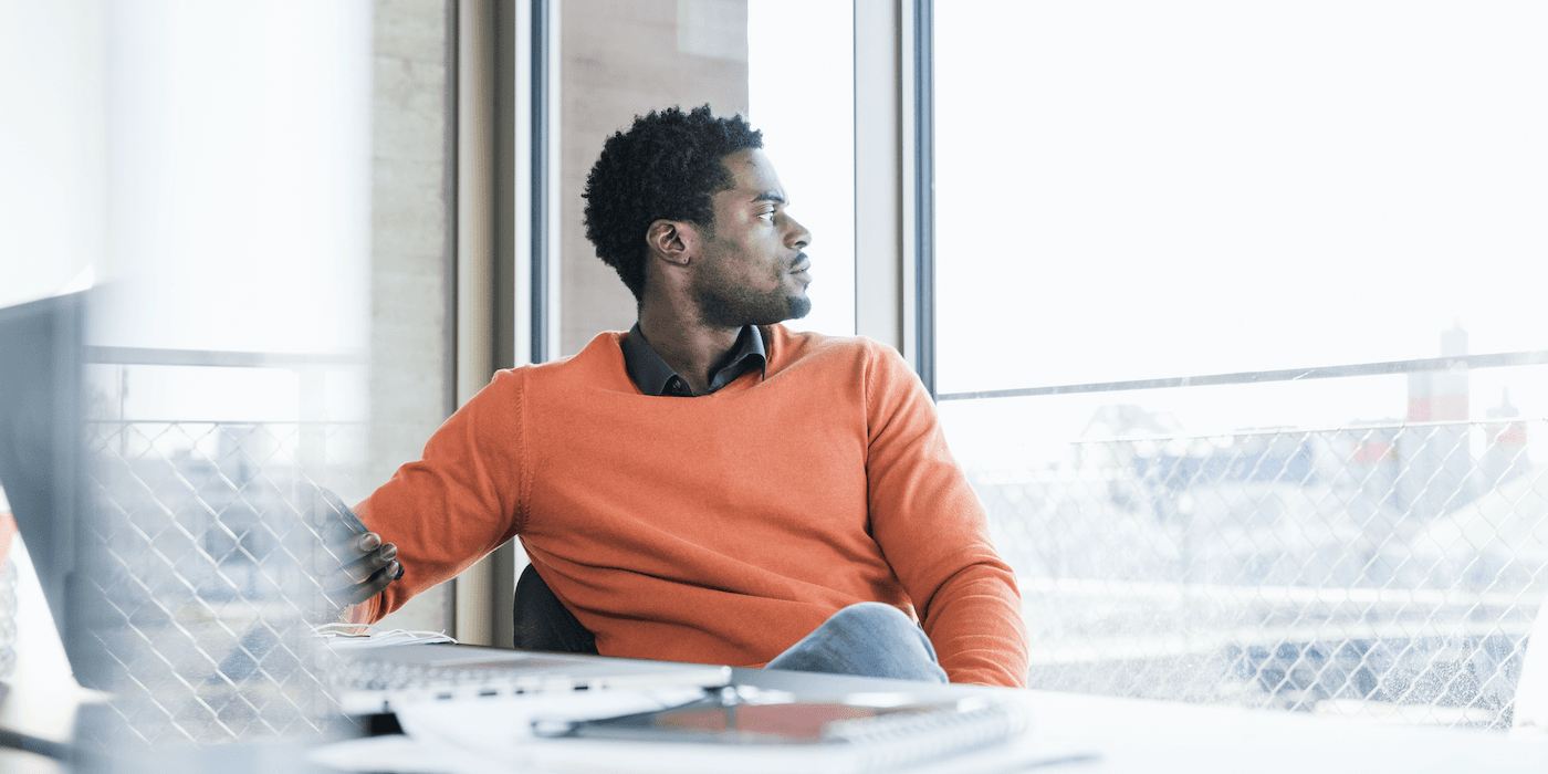 person sitting at work desk and staring out the window